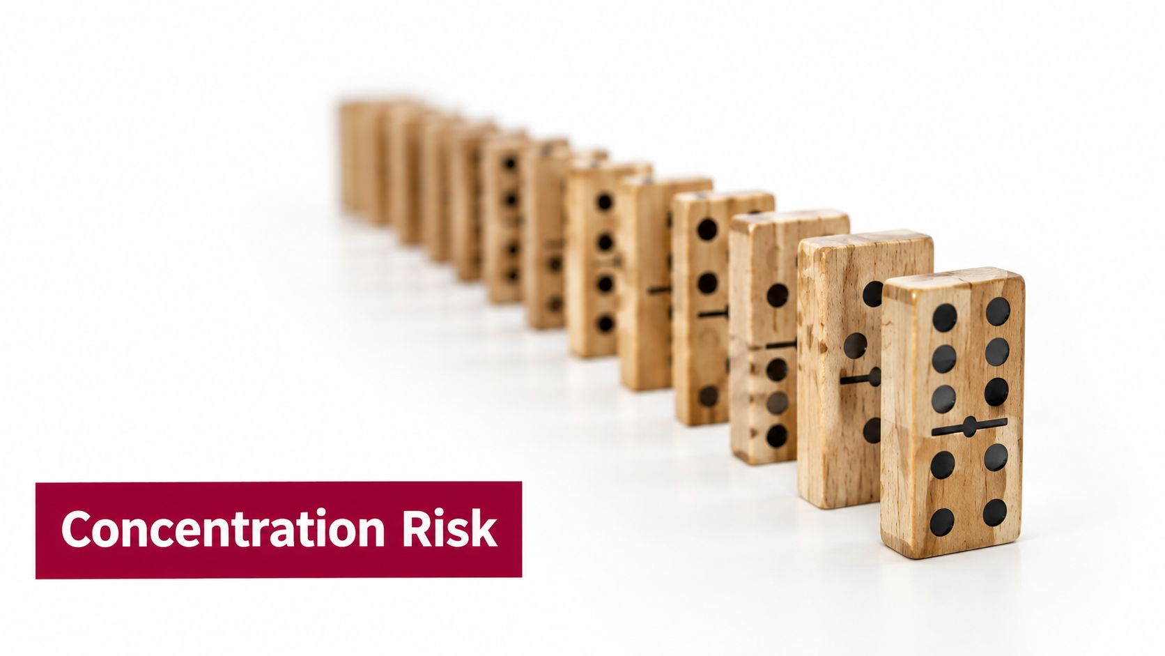A row of wooden dominoes standing on a white surface, illustrating the concept of concentration risk.