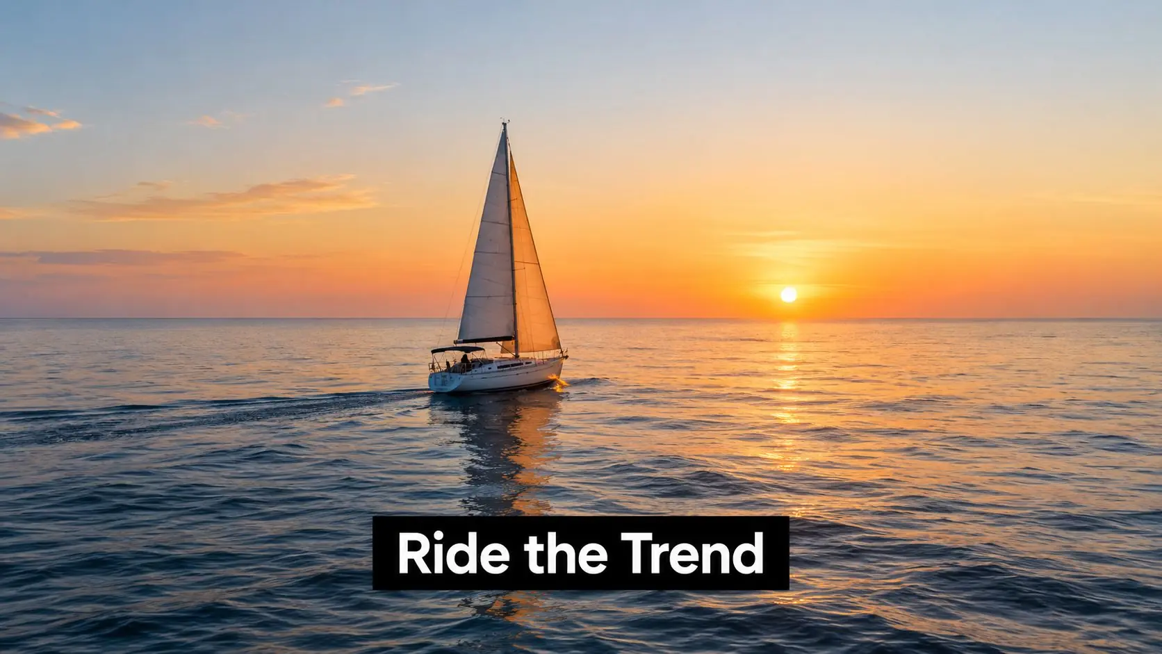 A sailboat glides across the calm, golden ocean water at sunset under a bright, clear sky.